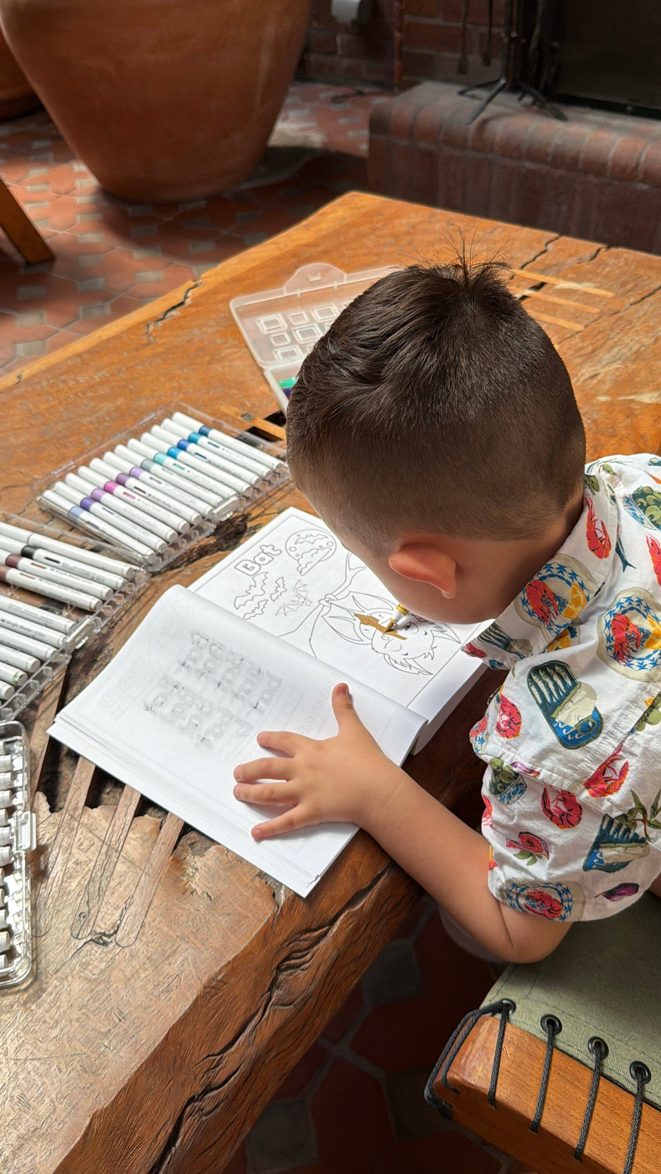 Child coloring a Bat from Animals, Insects and Ocean Friends Coloring Book for children on wooden table.