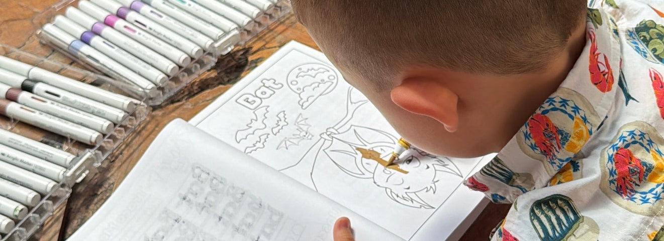 Child coloring a Bat from Animals, Insects and Ocean Friends Coloring Book for children on wooden table.
