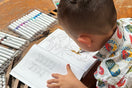Child coloring a Bat from Animals, Insects and Ocean Friends Coloring Book for children on wooden table.