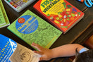 Child using Ermenrich Designs activity coloring books with crayons, glue, and scissors on table