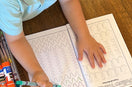 Child tracing lines inside Preschool Essentials coloring book for kids by Ermenrich Designs