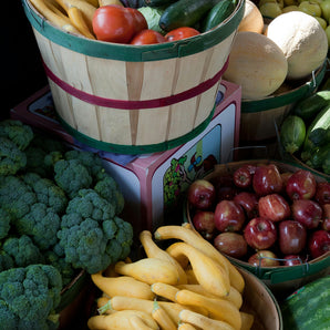 Assorted fresh vegetables and fruits in baskets, including squash, tomatoes, apples, broccoli, and melons