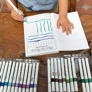 Toddler tracing lines activity coloring page from Preschool Essentials Trace Lines, Colors, Shapes, and Numbers Coloring Book: Spanish Version for children on wooden table.