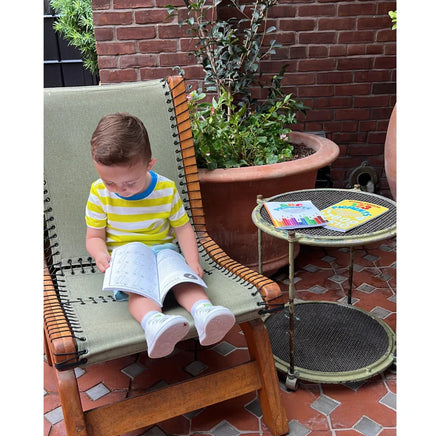 Toddler reading 123 Pigments: Spanish version coloring book by Ermenrich Designs. educational coloring book outdoors on lounge chair