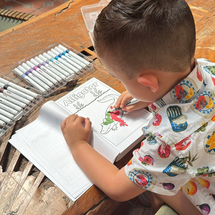 Child coloring Alligator coloring page from Animals, Insects and Ocean Friends Coloring Book from Ermenrich Designs on brown wood table. Ages 3+