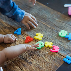 child reaching for the number 8 on a wooden table